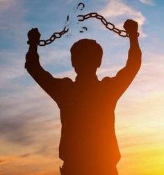 the silhouette of a man with his arms in the air and chains around his neck