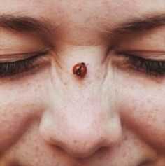 a ladybug is sitting on top of the nose of a woman's face