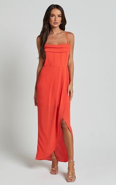 a woman is wearing an orange dress with one leg slited and the other side split open