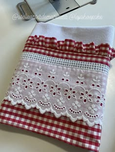 a piece of cloth with white lace on it sitting next to an old sewing machine