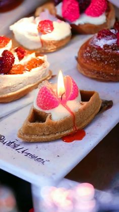 there are many desserts on the table with candles in front of them and one has a lit candle