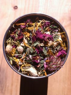 a metal bowl filled with lots of different colored flowers on top of a wooden table