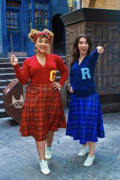 two women standing next to each other in front of a building