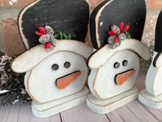 three snowmen with hats and bows on their heads are sitting next to each other