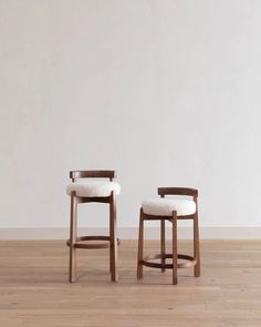 two wooden stools sitting on top of a hard wood floor next to each other