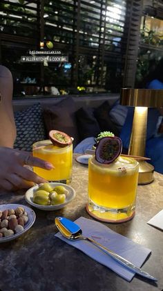 two people sitting at a table with plates of food and drinks