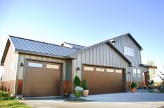 two garages in front of a large house with metal roofing and brown doors