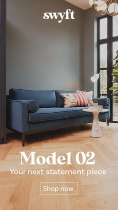 a blue couch sitting on top of a hard wood floor next to a table with a lamp