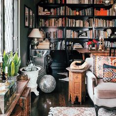 a living room filled with lots of furniture and bookshelves next to a window