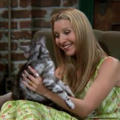 a woman sitting in a chair holding a gray and white cat with her eyes closed