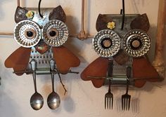 two metal owls hanging from hooks with forks and spoons attached to them, one has an owl face on it's head