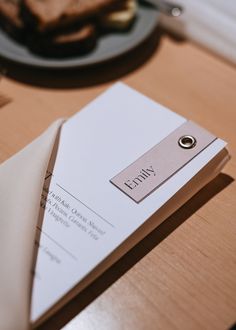 a piece of paper sitting on top of a wooden table next to a plate of food