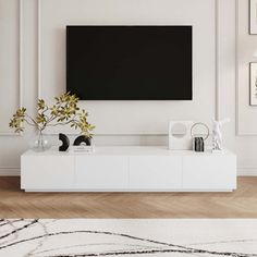 a living room with a large flat screen tv mounted on the wall and white furniture