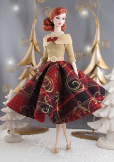 a doll is standing in front of some christmas trees and snow - covered ground, wearing a red plaid dress with gold accents