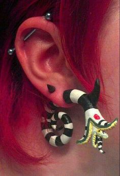 a close up of a person with red hair wearing ear piercings and black and white designs