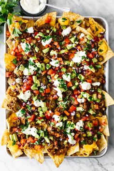 nachos on a tray with salsa and sour cream