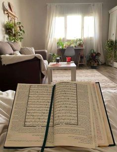 an open book sitting on top of a bed in a living room next to a window