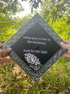 someone holding up a graduation cap that says, when you're lost in the darkness, look for the light