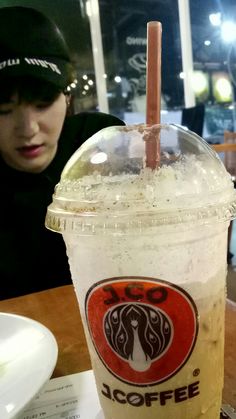 a starbucks iced drink sitting on top of a table next to a woman in a black hat