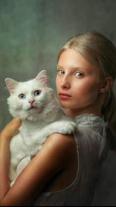 a woman holding a white cat in her arms and looking at the camera with an intense look on her face