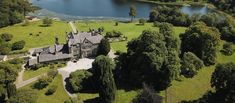 an aerial view of a large house in the middle of a forest with a lake behind it