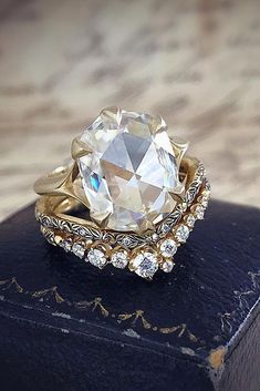 a ring with an oval cut diamond surrounded by smaller round diamonds on top of it