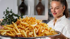 a woman holding a platter full of french fries