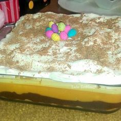 a cake with white frosting and colorful candies on top is sitting on a table