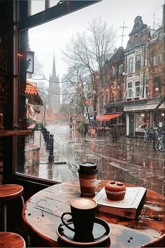 a cup of coffee sitting on top of a wooden table next to a large window