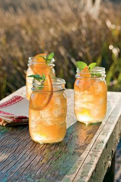 three jars filled with lemonade sitting on top of a wooden table