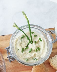 a bowl of mashed potatoes and asparagus on a cutting board with bread