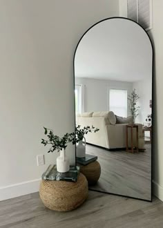 a mirror sitting on top of a wooden floor next to a vase filled with flowers