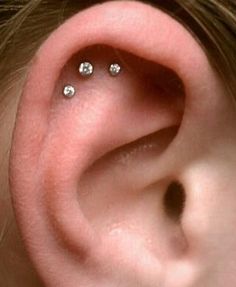 an ear with three piercings attached to it's side, and two smaller ones behind the ear