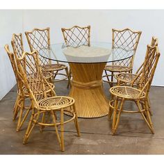 a round dining table with six chairs around it and a glass top on the side