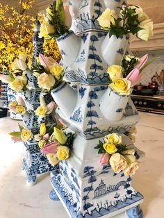 three blue and white vases with flowers in them on a marble counter top next to yellow flowers