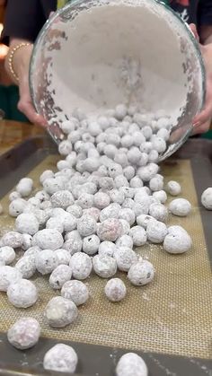 a person pouring water into a bowl filled with snowballs