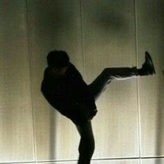 a man doing a trick on a skateboard in front of a wall with shadows