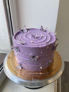 a purple cake sitting on top of a metal plate next to a window sill