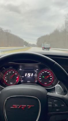 the dashboard of a car driving on a road with trees in the backgroud