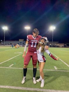 a couple of people that are standing on a field with some lights in the background