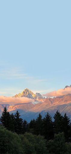 the mountains are covered in clouds and trees