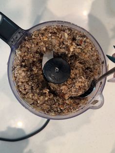 a blender filled with granola on top of a white counter next to flowers