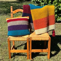 two crocheted pillows sitting on top of a wooden chair next to each other