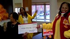 two women in yellow jackets holding up a large cheque for $ 1, 000