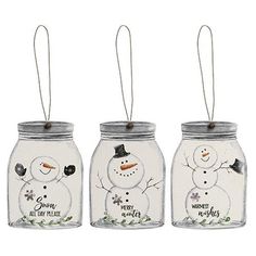 three snowman mason jars are hanging from strings