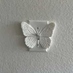 a white butterfly is mounted to the wall