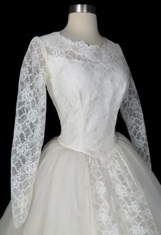 a white wedding dress on a mannequin headdress with long sleeves and lace