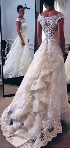 a woman standing in front of a mirror wearing a wedding dress with ruffles