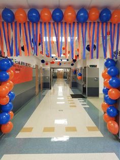 the hallway is decorated with balloons and streamers for an orange, blue, and white party