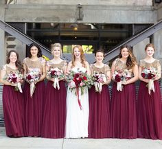 a group of women standing next to each other holding bouquets in front of a building